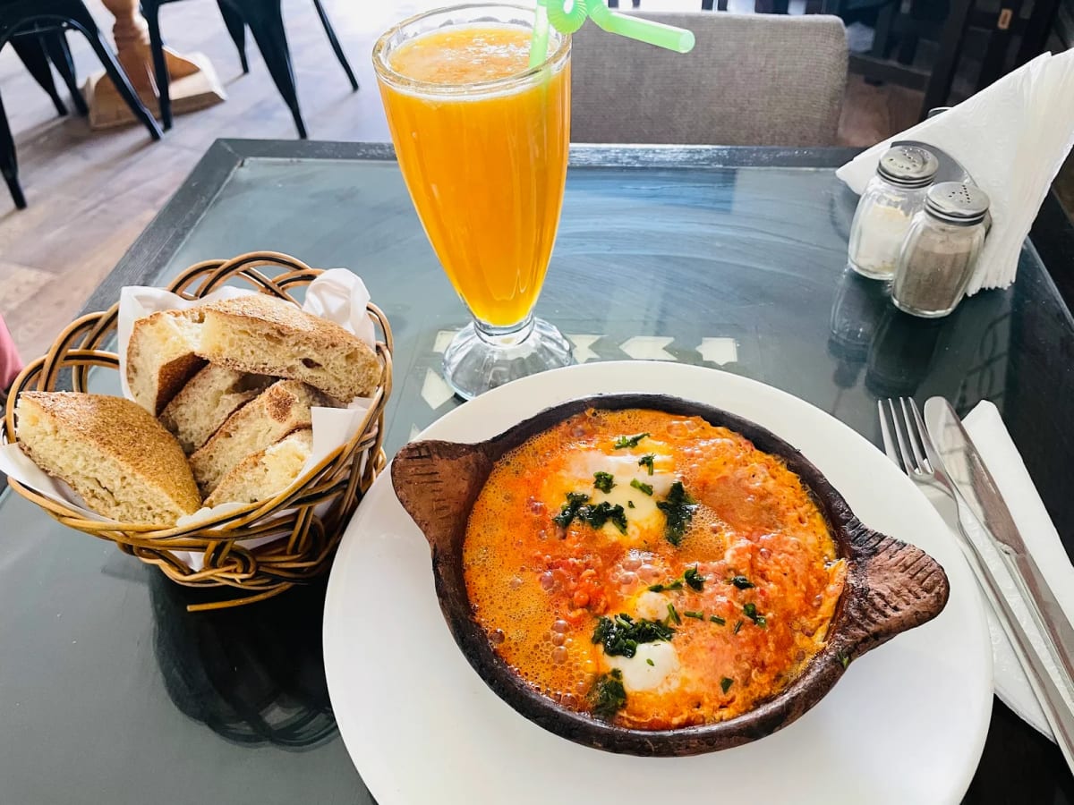 Chakchouka servie avec jus d'orange frais et pain marocain