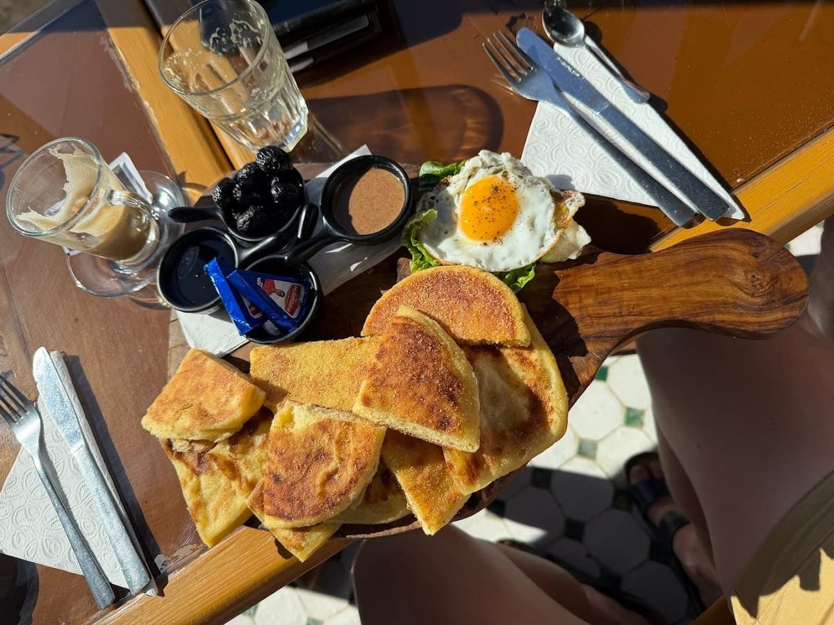Petit déjeuner marocain servi sur planche en bois avec msemen, œuf et thés