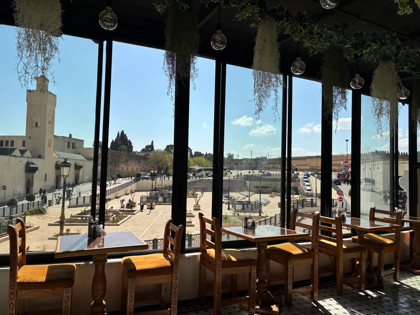 Salle lumineuse du Medina Cafe avec grandes baies vitrées donnant sur la place de Boujloud et le minaret
